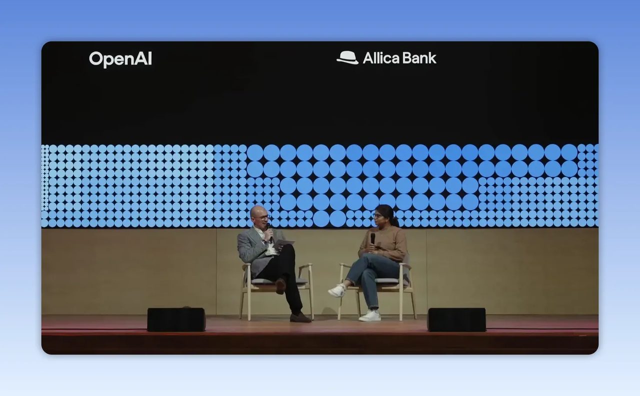เวทีสนทนาที่มีโลโก้ OpenAI และ Allica Bank อยู่ด้านบน พร้อมผู้ร่วมเสวนาสองคนนั่งบนเก้าอี้