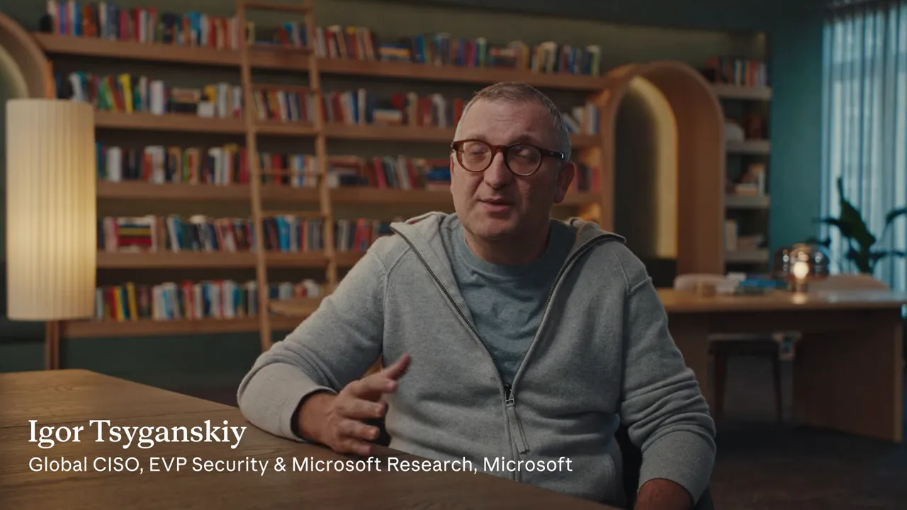 ผู้ให้สัมภาษณ์หน้าชั้นหนังสือ พร้อมป้ายชื่อ Igor Tsyganskiy และตำแหน่งที่ Microsoft