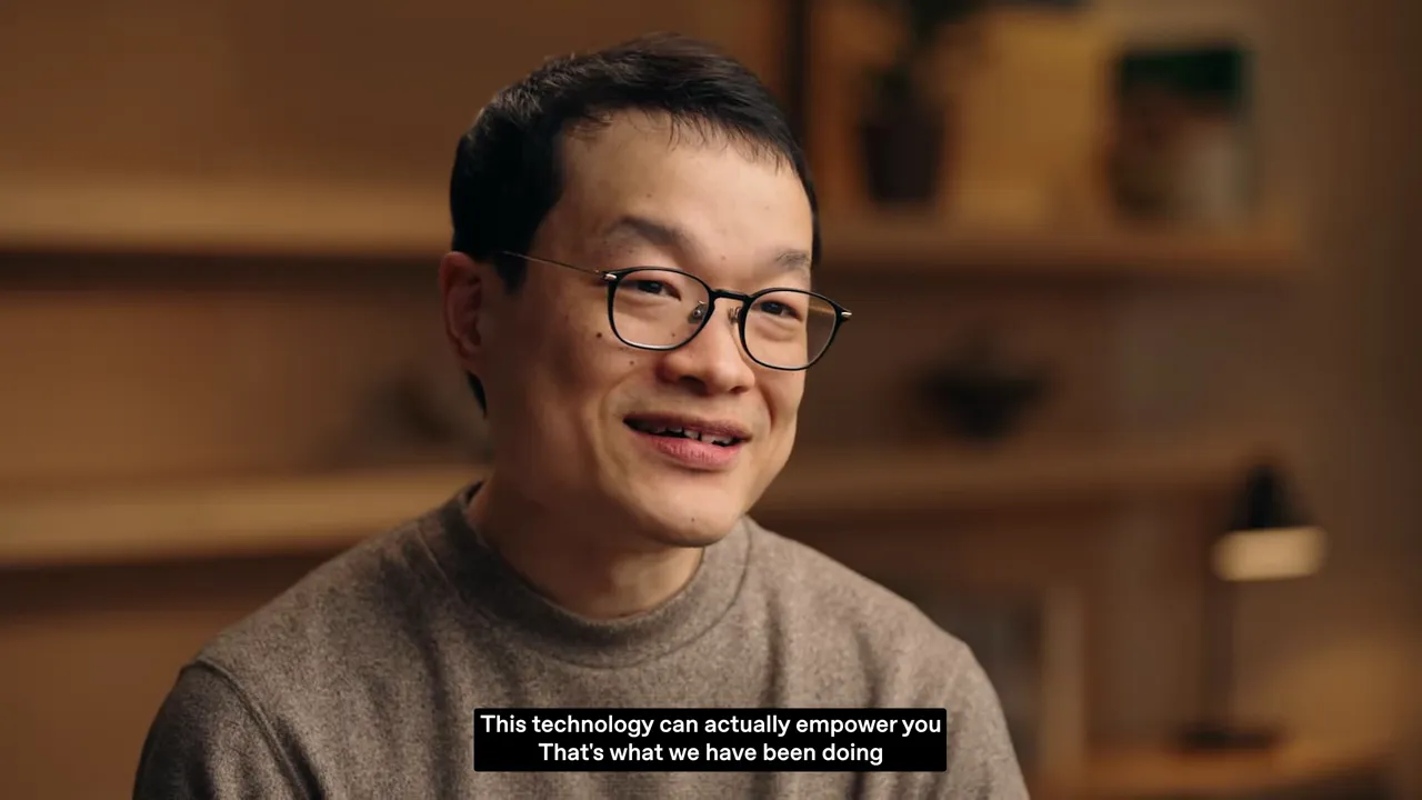 Close-up interview shot of a smiling speaker with on-screen subtitle 'This technology can actually empower you'.